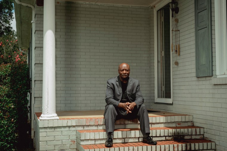 Terry Belk sits on the steps of his home