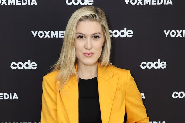 Olivia Nuzzi looks at the camera wearing a yellow blazer over a black shirt.