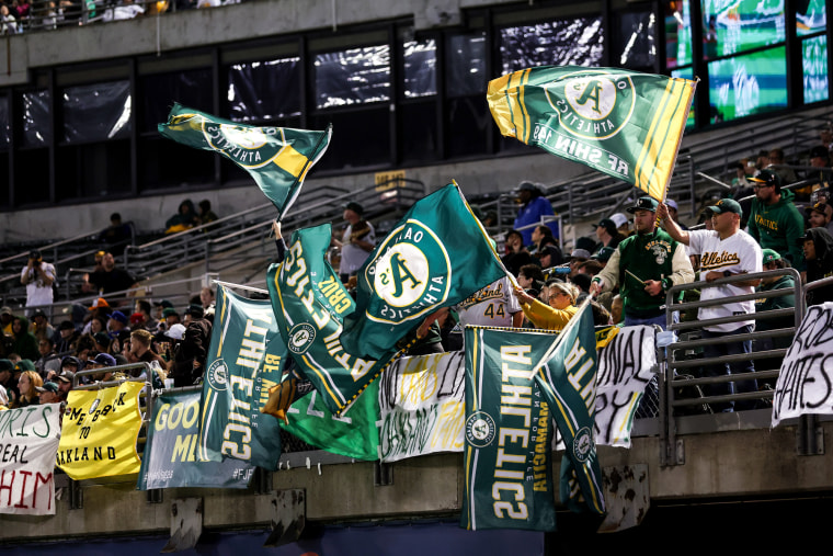 Fans wave Oakland Athletics fans in the stands of a stadium