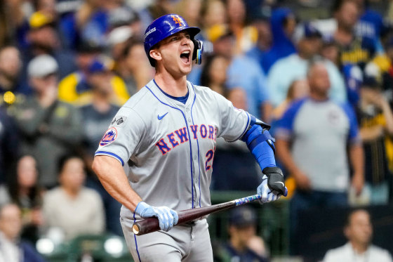 Pete Alonso celebrates on the field holding the baseball bat in both hands