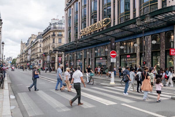 A busy crosswalk in front of a building with a sign that says “Samaritaine.”