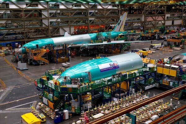 A view from above of people assembling planes in a large industrial space.