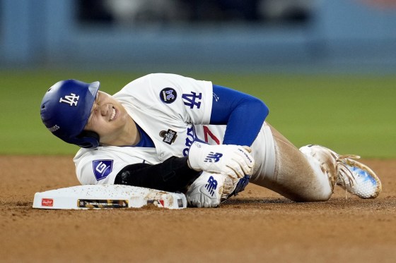 Los Angeles Dodgers' Shohei Ohtani holds his arm after being injured while trying to steal second base.