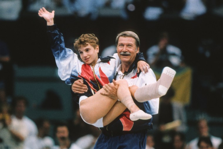 Kerri Strug, wearing an injury boot, is carried by Bela Karolyi