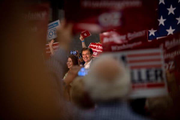 Dr. Mehmet Oz is seen surrounded by campaign signs and U.S. flags.