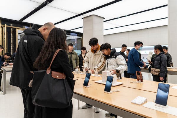 Shoppers look at phones on display in a well-lighted store.