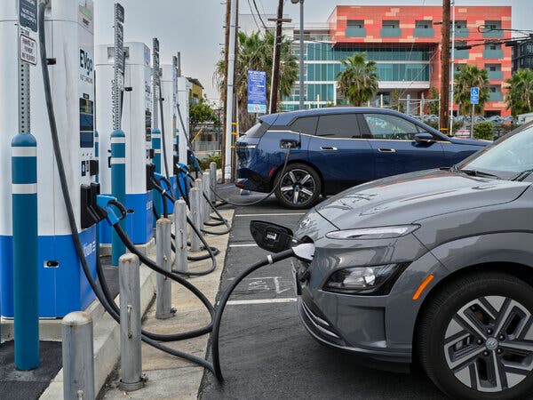 Two electric vehicles, one gray and the other navy blue, parked at chargers.