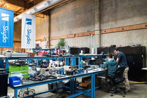 People at a large work station with many gadgets and wires. Banners hanging from the ceiling say “Skydio.”