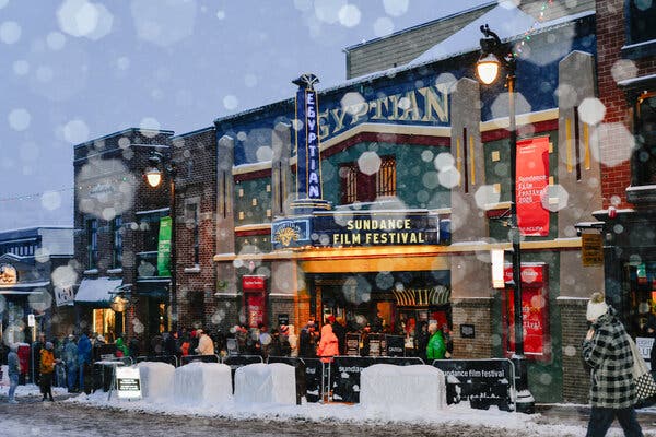 28sundancemove-02-kzjf-articlelarge A snowy street scene, showing a crowd outside a movie theater called the Egyptian, with a sign that says “Sundance Film Festival.”