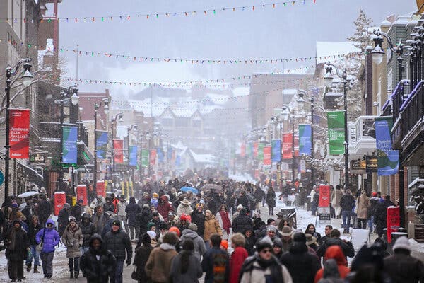 28sundancemove-03-kzjf-articlelarge Crowds of people, bundled in winter clothing, fill a street lined with streetlamps and modest buildings, with many signs promoting the Sundance Film Festival.