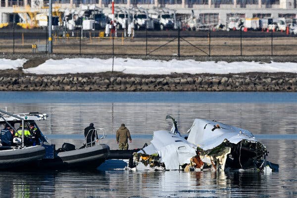 30crash-safetynet-01-jlwt-articlelarge People on a boat float beside wreckage of a plane along the snowed-over bank of a waterway.
